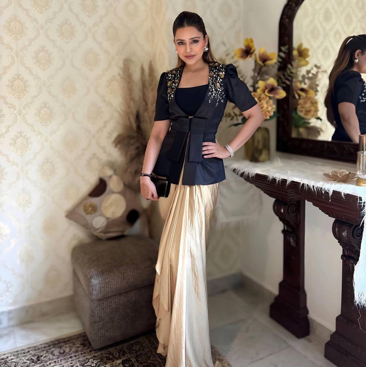 Woman in a black and beige outfit standing in a room with decorative elements.