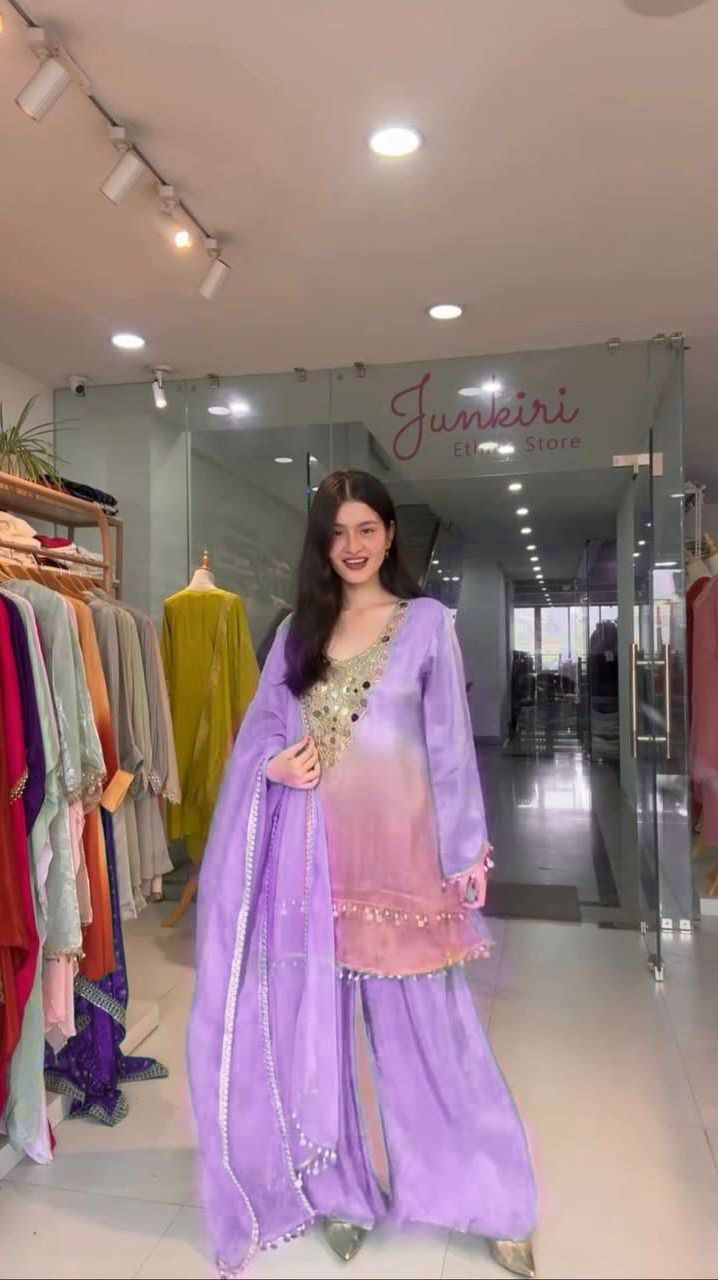 Woman in a purple traditional outfit standing in a store with 'Junkeri' branding.